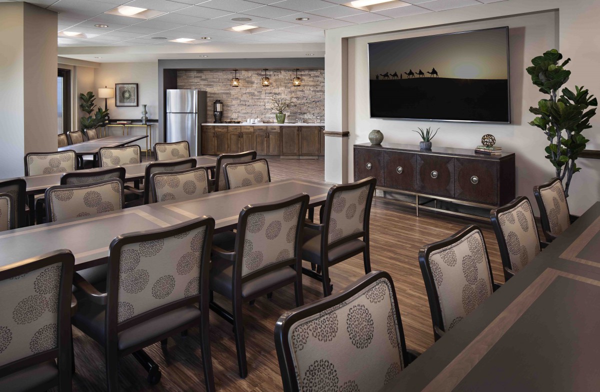 A modern conference room featuring a kitchenette and audiovisual equipment.