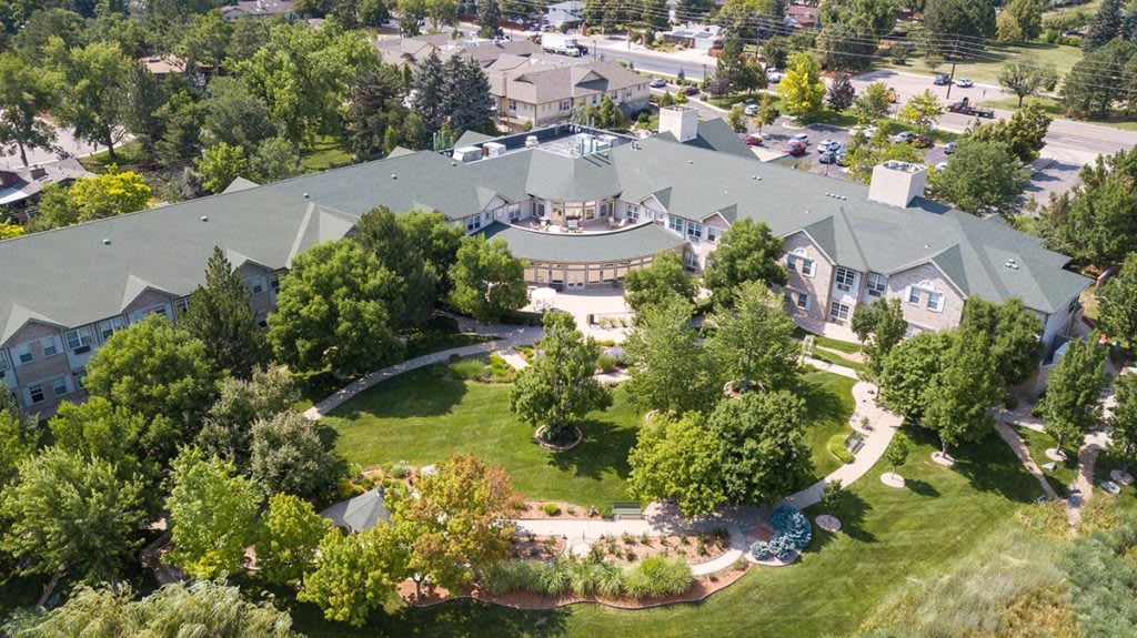 Aerial view of a large building surrounded by lush greenery and landscaped gardens.