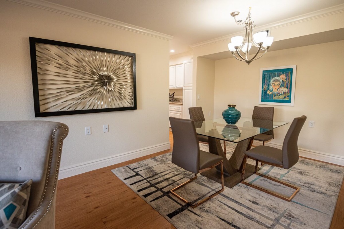 A contemporary dining room with a glass table, stylish chairs, and decorative artwork on the walls.