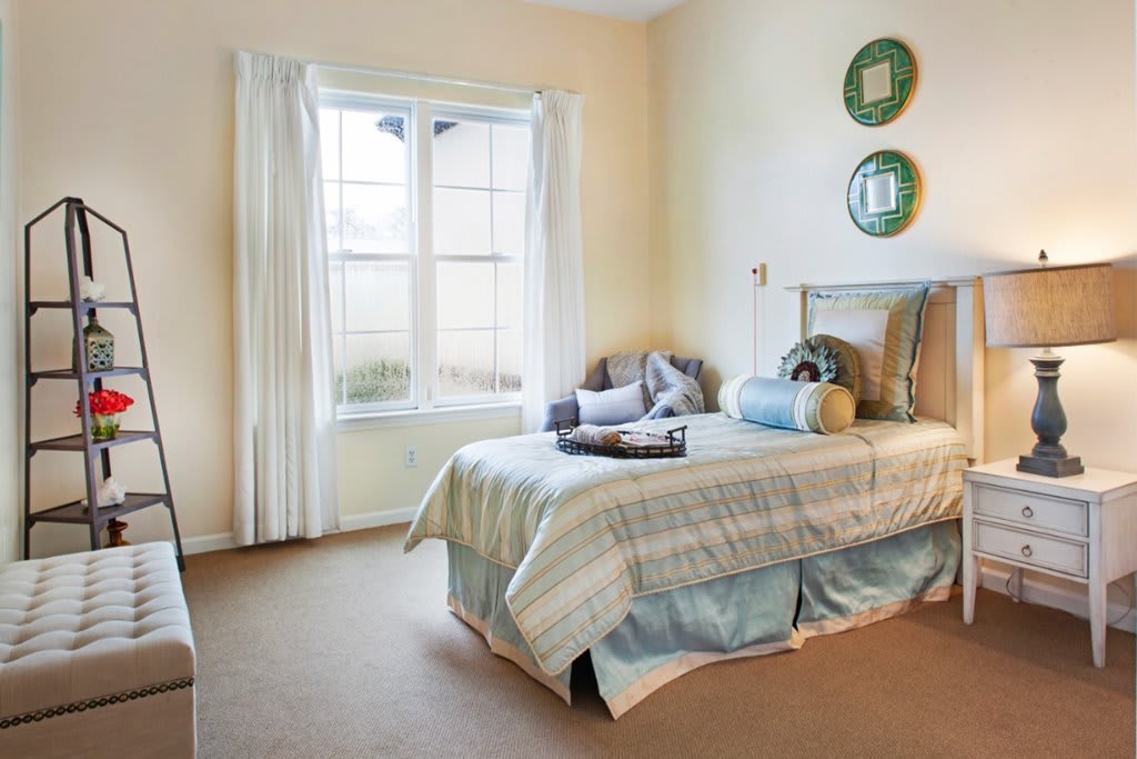 A cozy bedroom with a neatly made bed, soft lighting, and decorative plates on the wall.