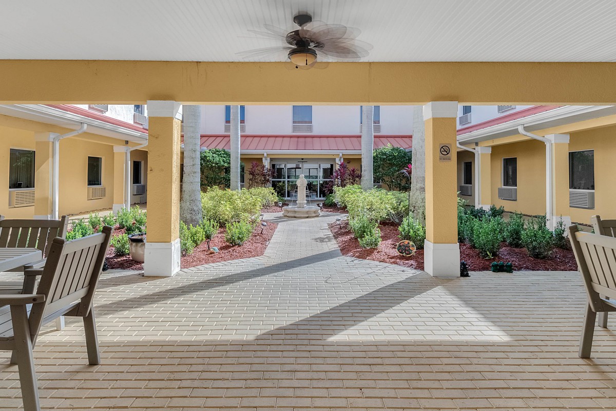 A well-maintained entrance with a landscaped garden and pathway, flanked by columns.