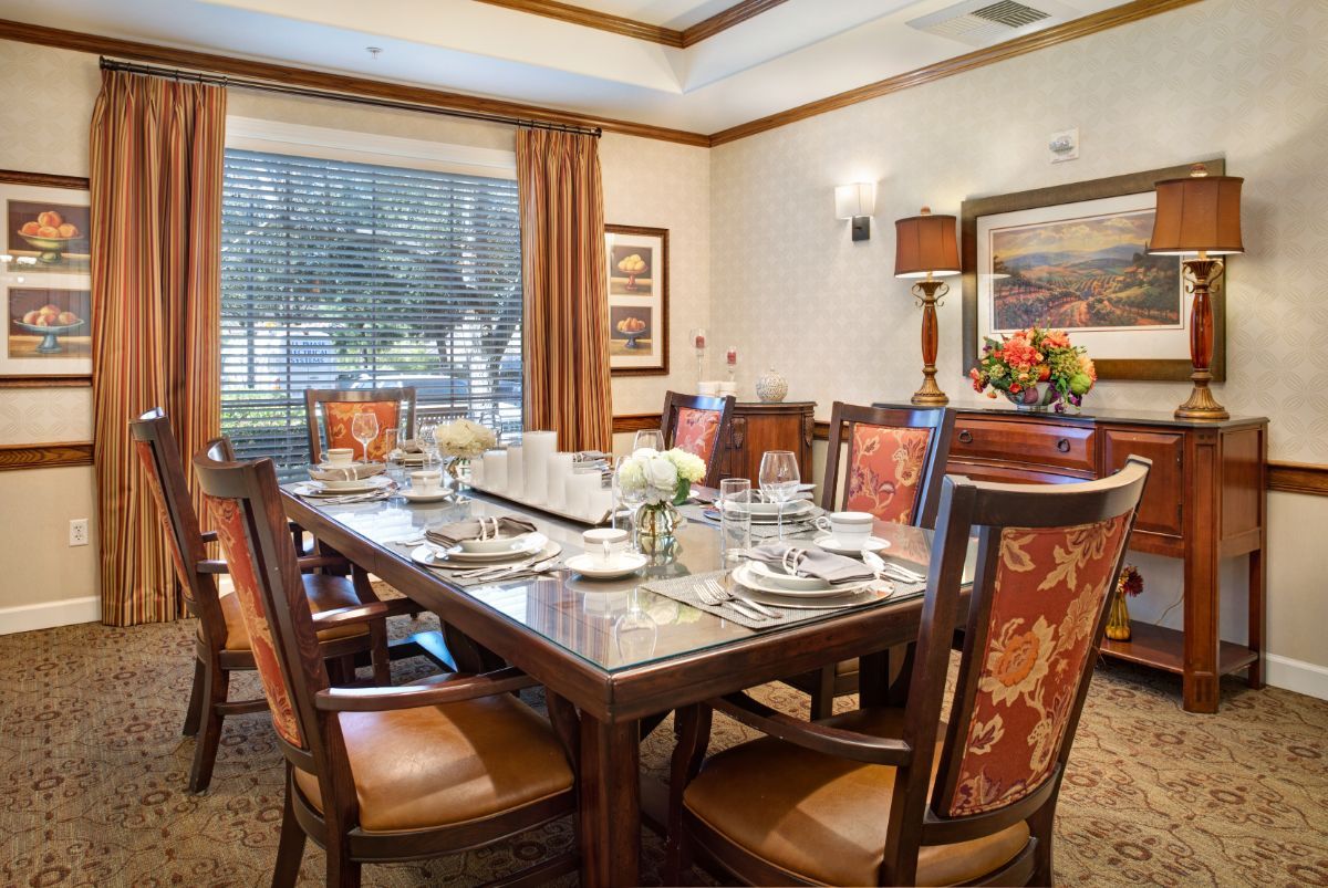 A formal dining room with a large table set for a meal, featuring elegant decor and artwork on the walls.