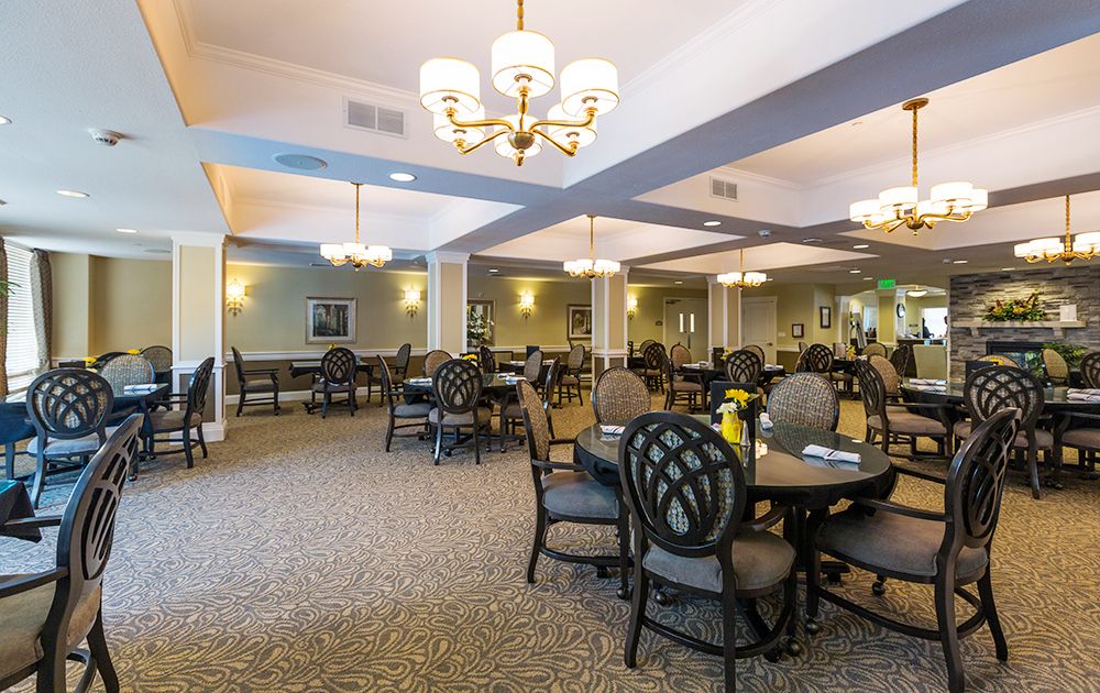 A spacious dining room with elegant chandeliers and neatly arranged tables and chairs.