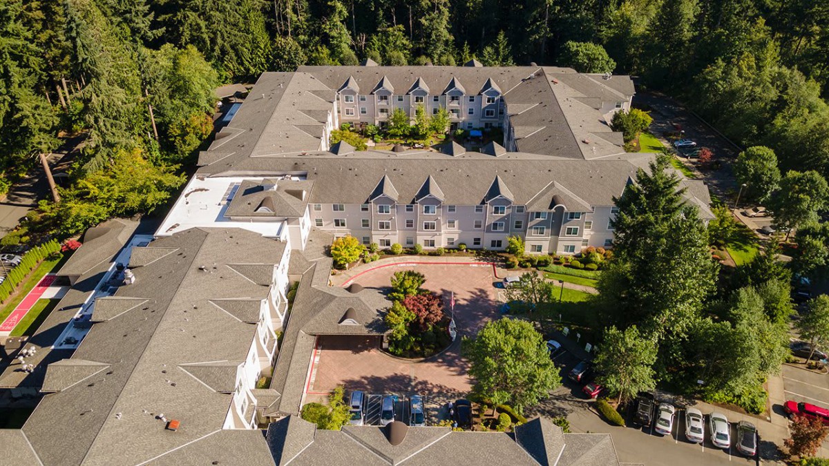 Aerial view of a large residential building surrounded by lush greenery and gardens.