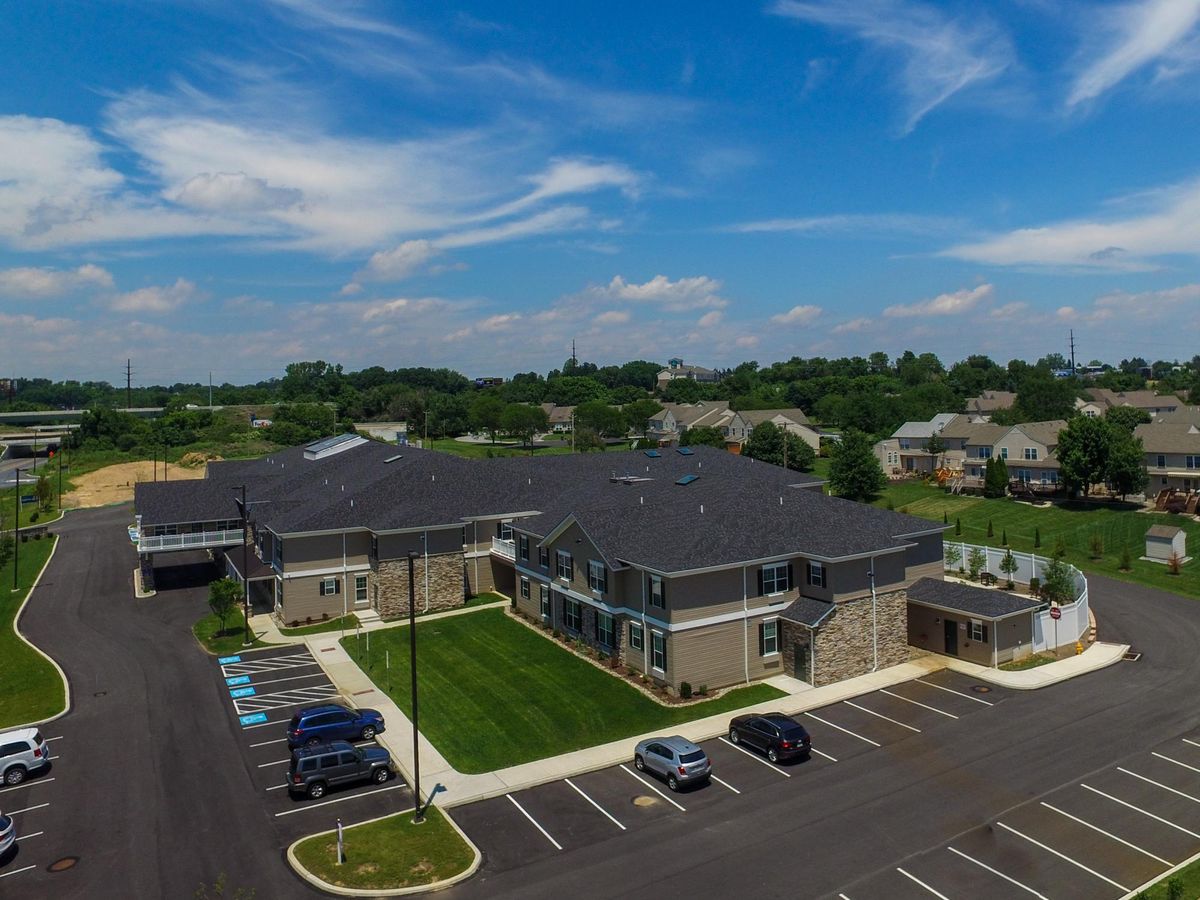 Aerial view of a suburban building with adjacent parking lot under a partly cloudy sky.