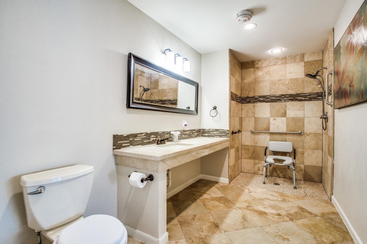 A modern bathroom featuring a double sink, large mirror, and tiled shower area.