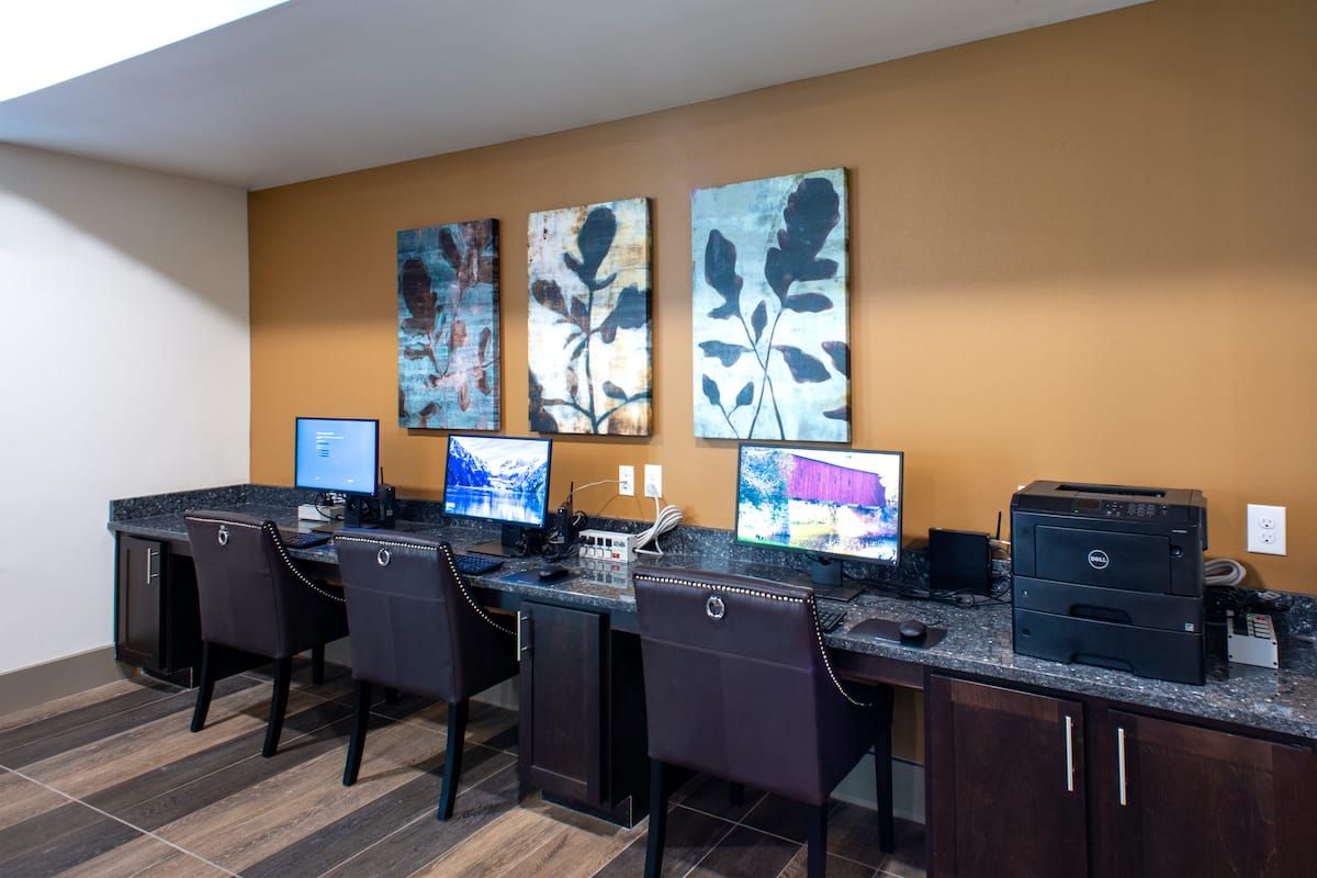 A modern business center with multiple workstations featuring computers and chairs, ideal for productivity.