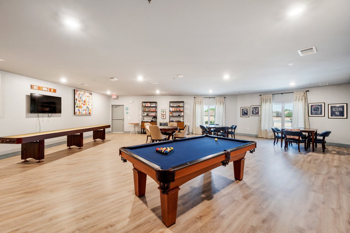 Spacious game room featuring a pool table and shuffleboard with elegant wood flooring.