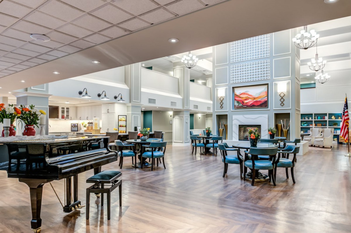 A spacious lobby with modern decor, featuring a piano, dining area, and fireplace.