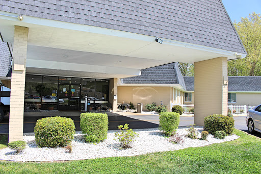 A modern building entrance with landscaped greenery and a surveillance camera.