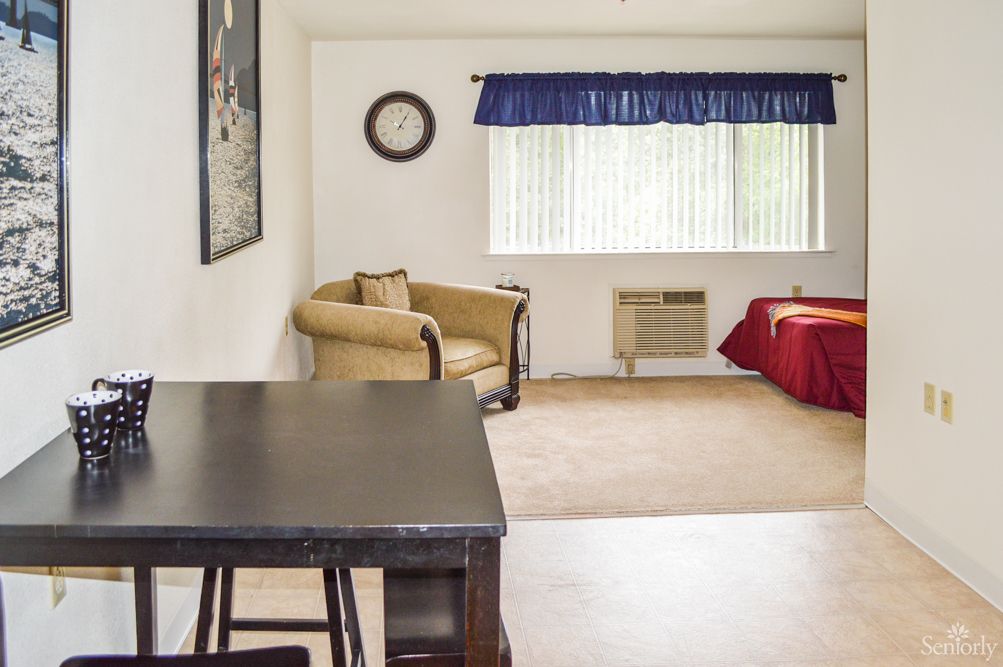 A cozy living room with a chair, table, and a window adorned with blue curtains.