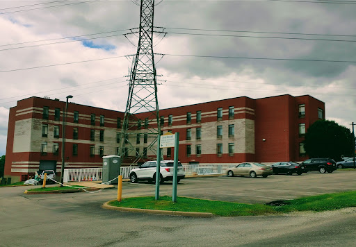 A view of a brick building surrounded by power lines and vehicles in an urban setting.