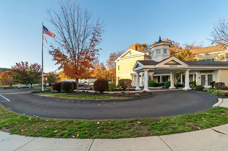 A quaint building with a porch, surrounded by autumn trees and an American flag.