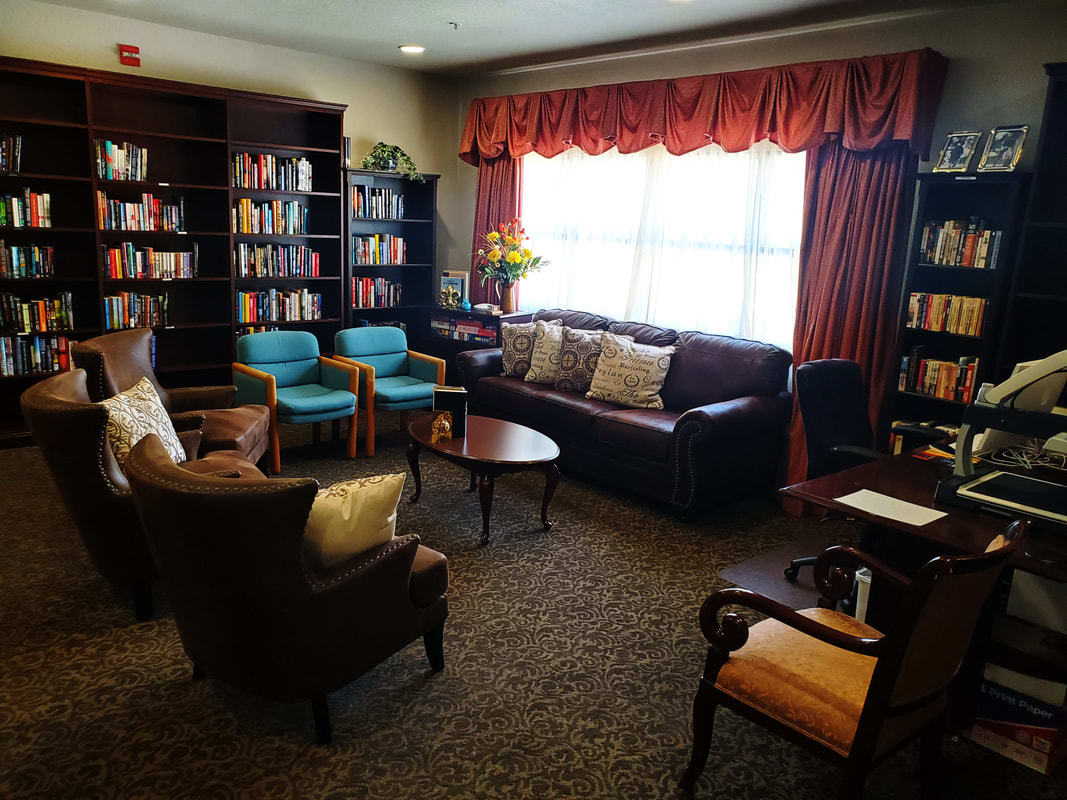 A cozy library with comfortable seating and shelves filled with books.