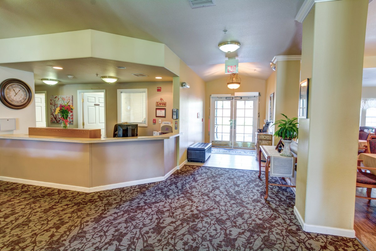 A spacious and well-lit lobby with a carpeted floor, featuring a reception desk and comfortable seating.