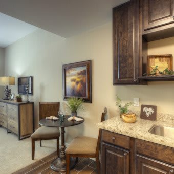A cozy interior space featuring a small seating area with a table, chairs, and wooden cabinetry alongside decorative artwork.
