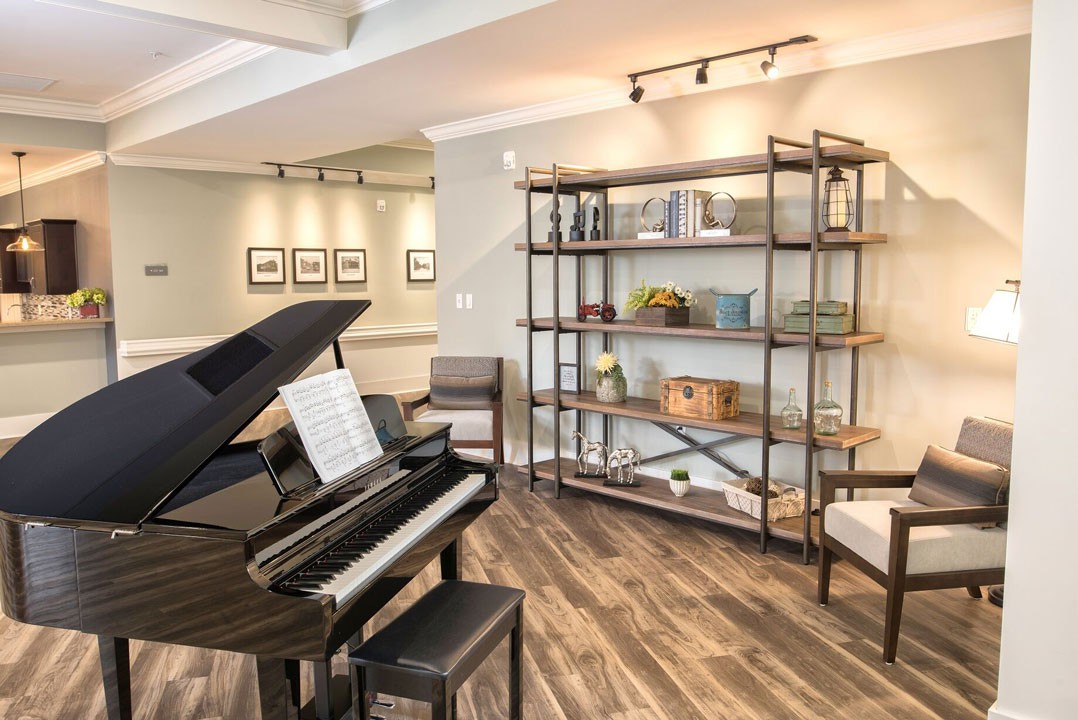 A cozy living room with a grand piano and decorative shelving.
