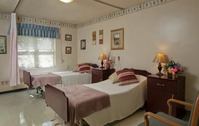 A hospital room with two beds, lamps, and decorative elements on the wall.