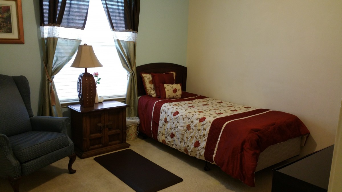 A cozy small bedroom with a single bed, nightstand, and window curtains.
