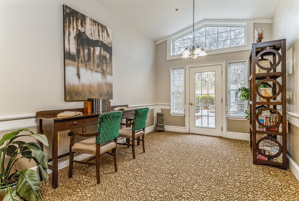 A cozy living room with elegant decor, featuring a painting, chairs, and ample natural light.