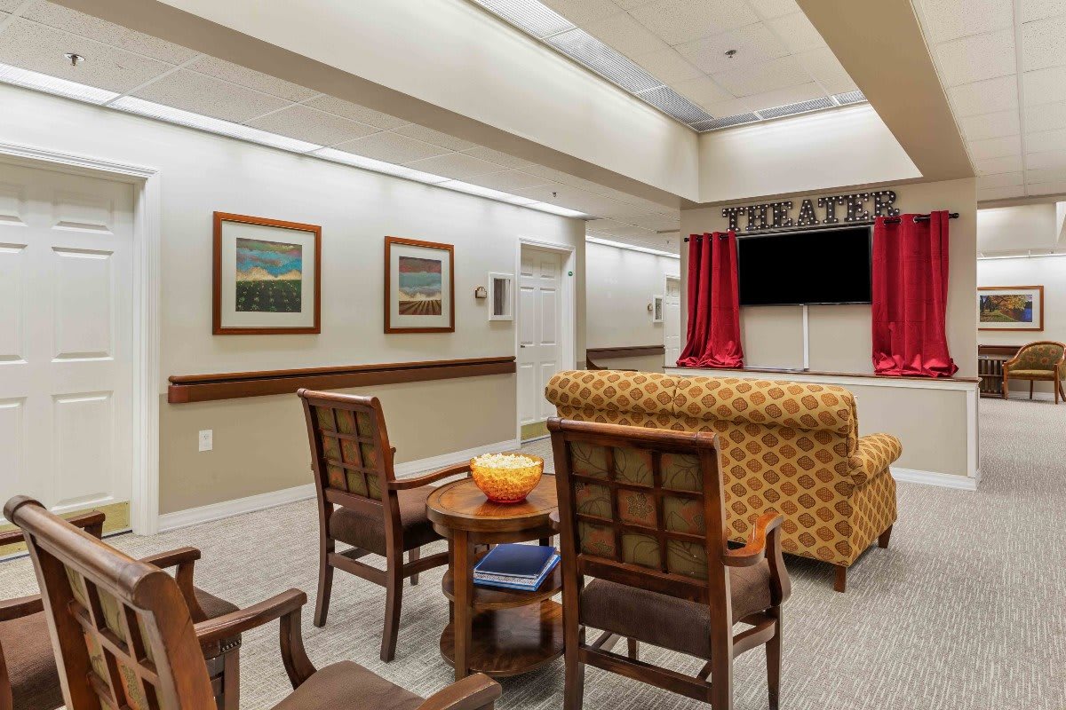A cozy indoor theater room with seating and a large television, decorated with artwork.