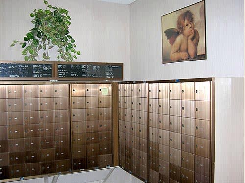 A lobby area featuring rows of mailboxes, a decorative plant, and a painting on the wall.