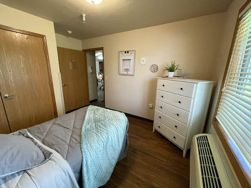 A cozy and well-decorated bedroom featuring a comfortable bed, stylish dresser, and warm wooden flooring.