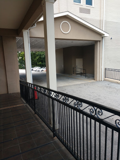 A view of a building's balcony overlooking a parking area.