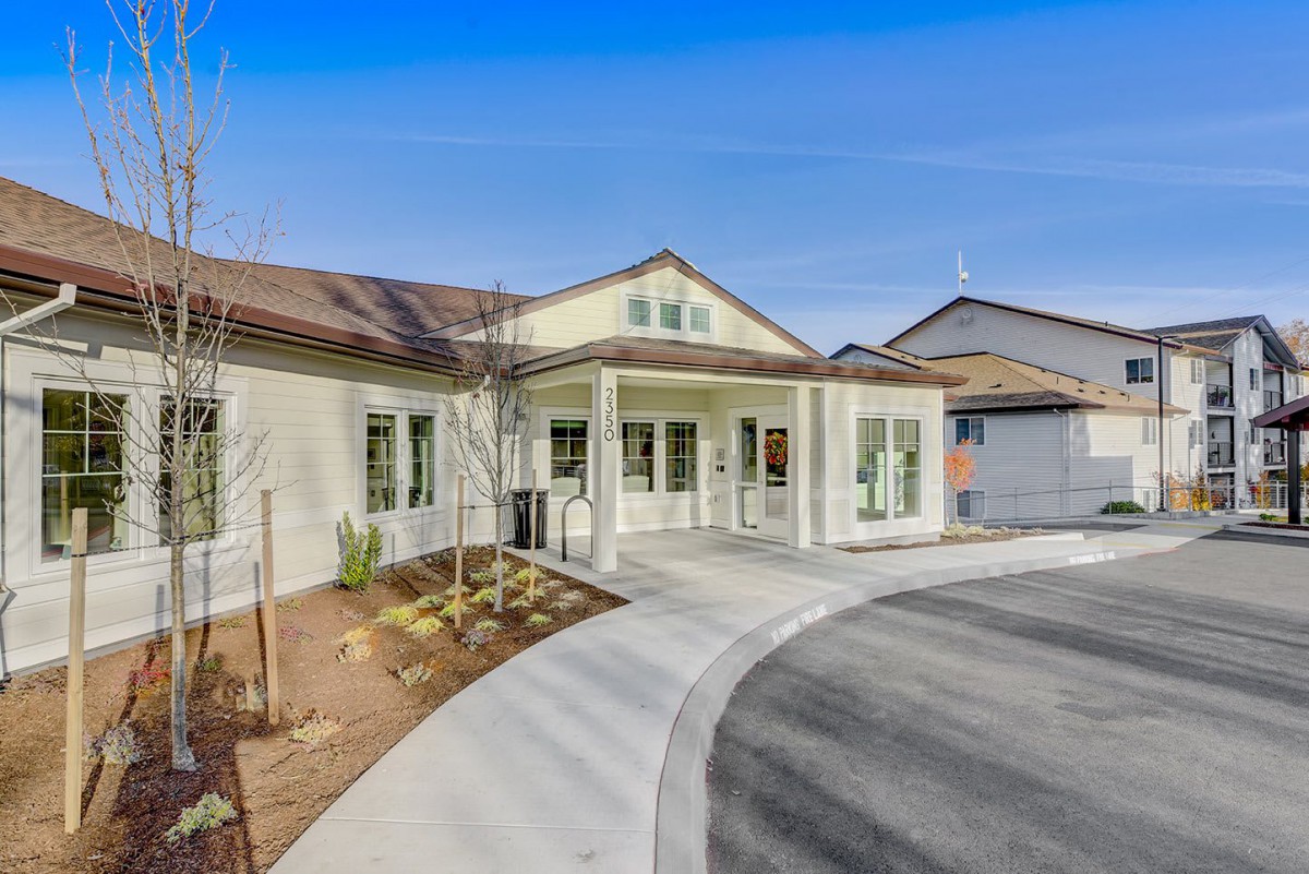 A modern residential building with a circular driveway and landscaped front yard.