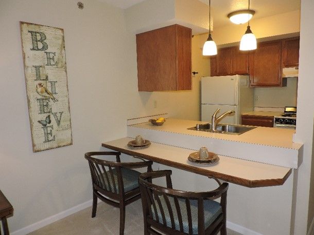 A cozy kitchen space with a dining counter and chairs, accented by pendant lighting.