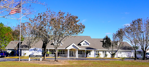 A charming residential building surrounded by trees under a clear blue sky.