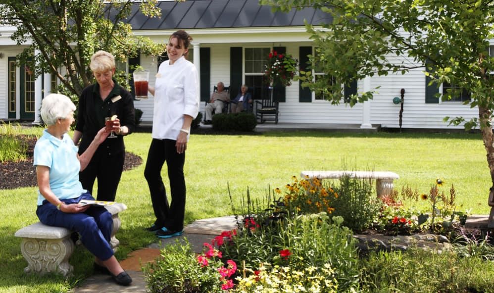 A group of people enjoying a conversation in a garden setting outside a house.