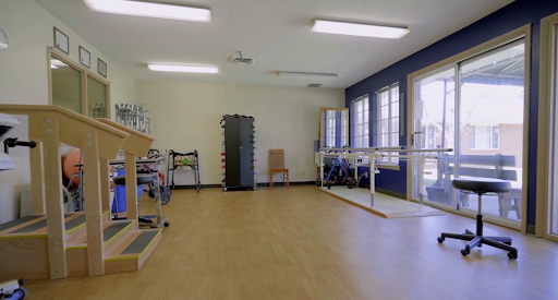A well-lit physical therapy space equipped with various rehabilitation tools and exercise apparatus.