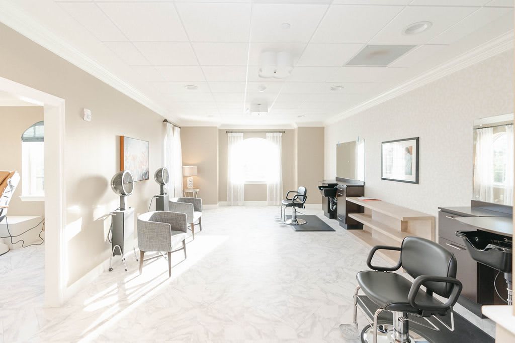A bright and modern salon interior with chairs, mirrors, and hair dryers.
