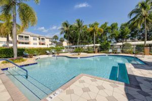 A relaxing tropical swimming pool area at a resort on a sunny day.