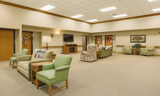 A spacious and cozy lounge area featuring green chairs and soft lighting.