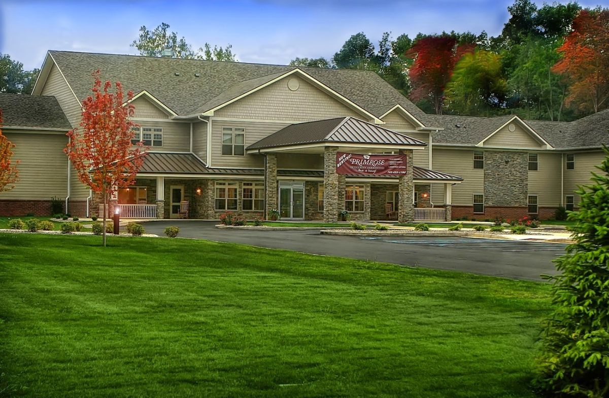 A hotel building with a surrounding landscape of grass and trees.