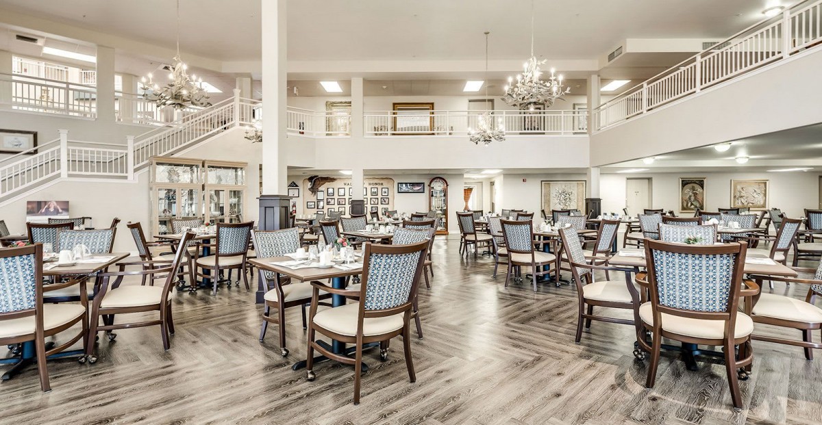A spacious and elegantly designed dining room with tables and chairs under a chandelier.