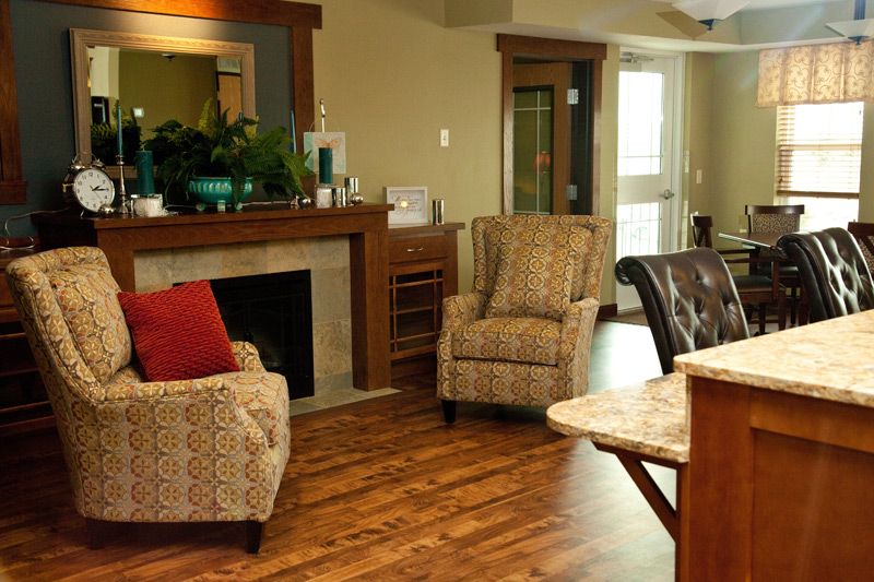 A cozy living room with armchairs and a fireplace, featuring hardwood flooring.