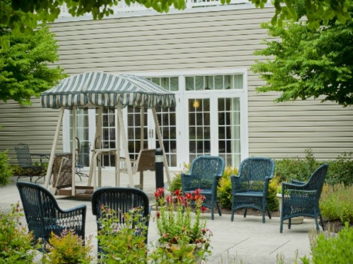 A tranquil patio space with a swing, blue chairs, and lush greenery.