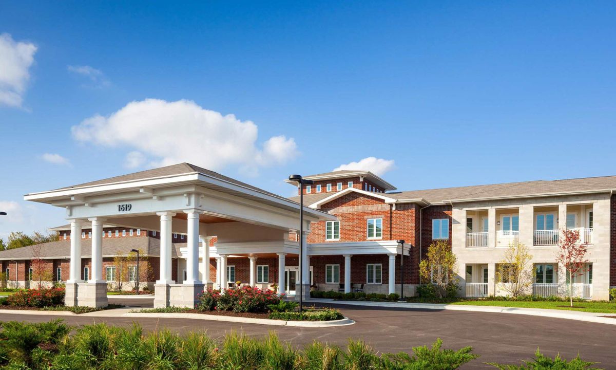 A modern residential building with a spacious entrance and clear blue skies.