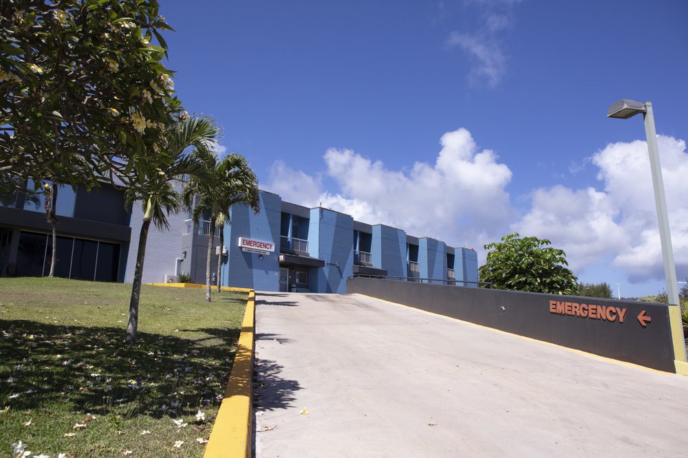 A blue building with palm trees under a partly cloudy sky.