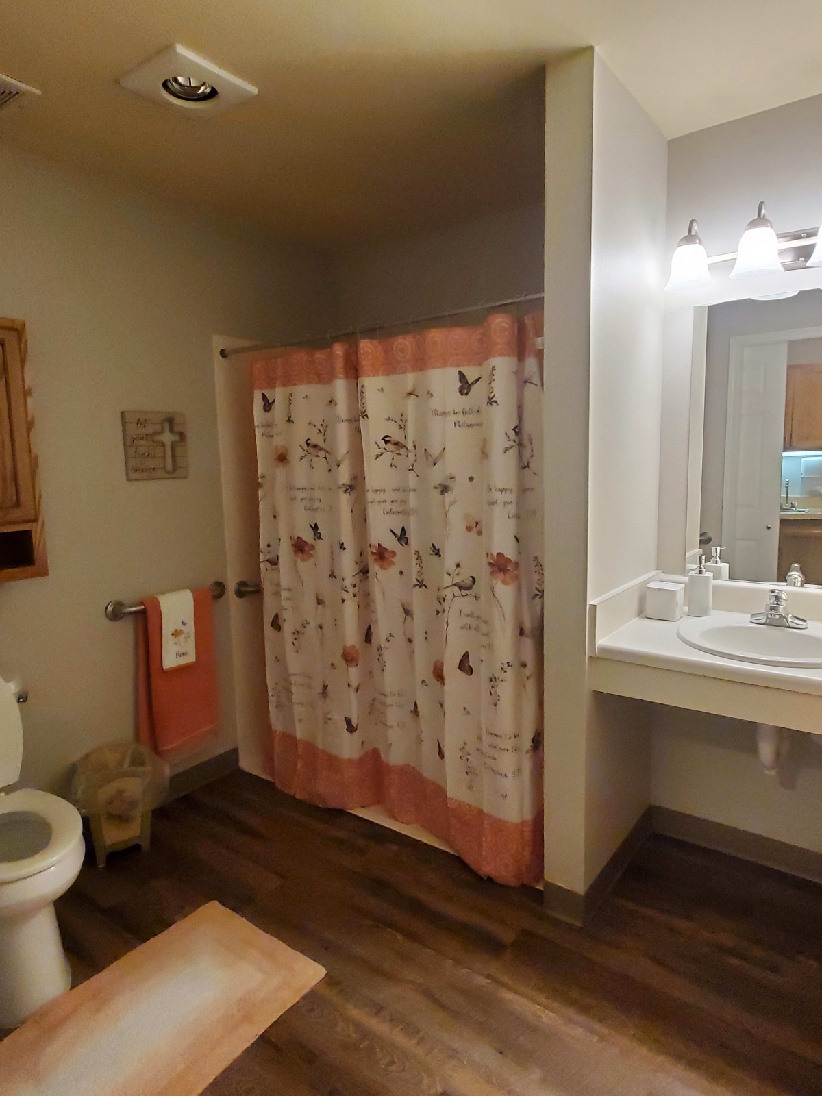 A cozy bathroom with a pink shower curtain and neatly arranged towels.