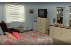 A cozy bedroom with a floral bedspread, dresser, and television.