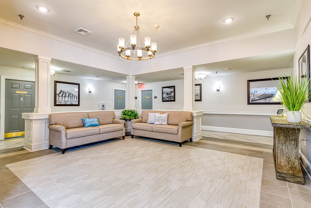 A modern living room with neutral-toned sofas, a stylish chandelier, and decorative wall art.