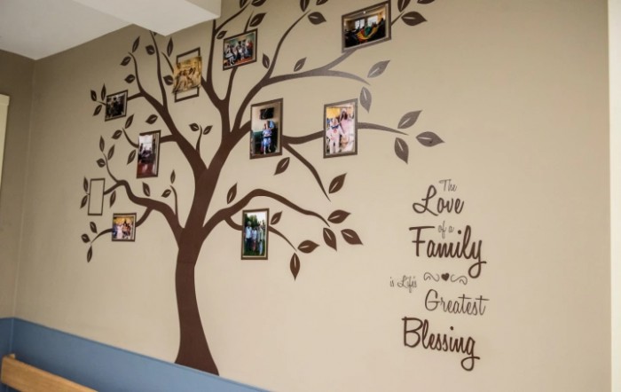 A beautifully decorated wall featuring a family tree with framed photos and an inspirational quote.