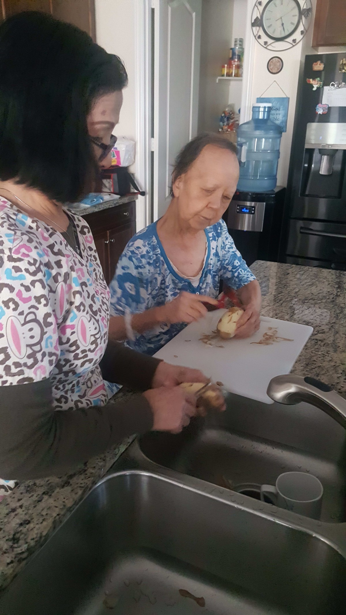 Two people peeling potatoes in a kitchen.