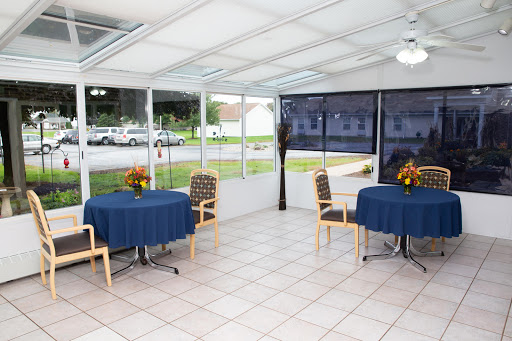 A cozy sunroom dining area with blue tablecloths and a bright atmosphere.