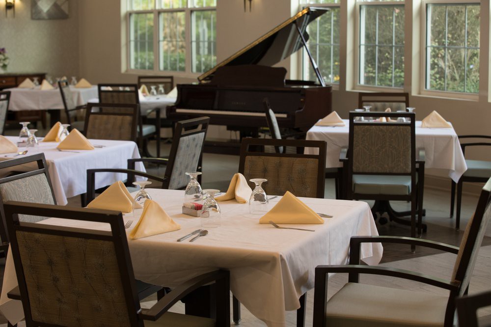 An elegant restaurant interior with neatly set tables and a grand piano in the background.