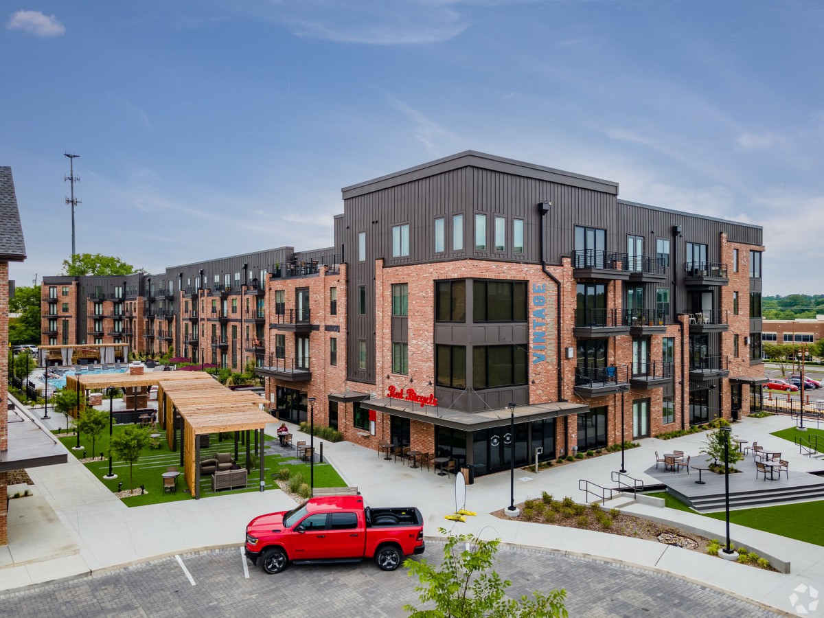 A modern apartment complex with a red truck parked outside and an outdoor seating area.